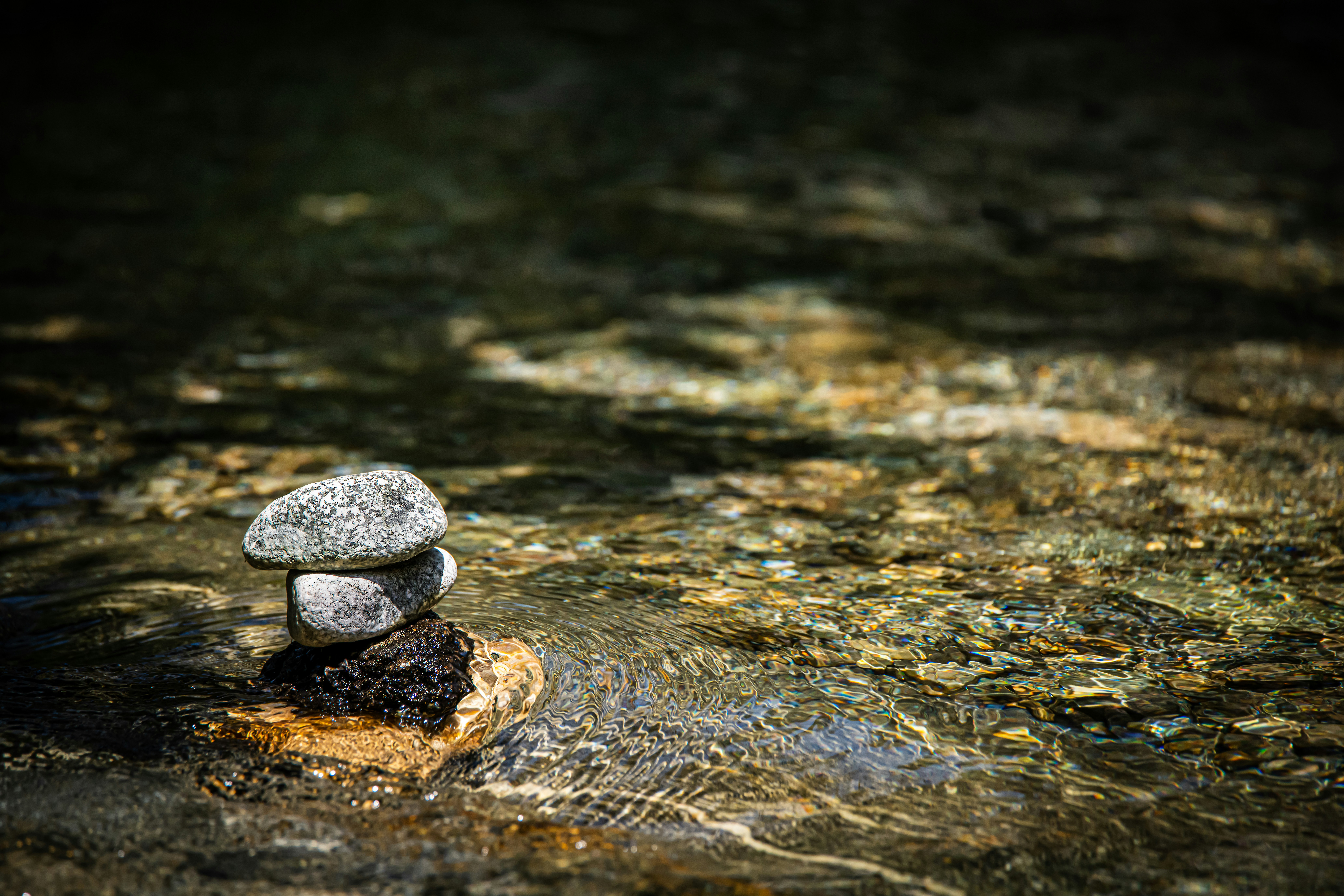 Close up of a rock pile in a river with the clear water flowing around it